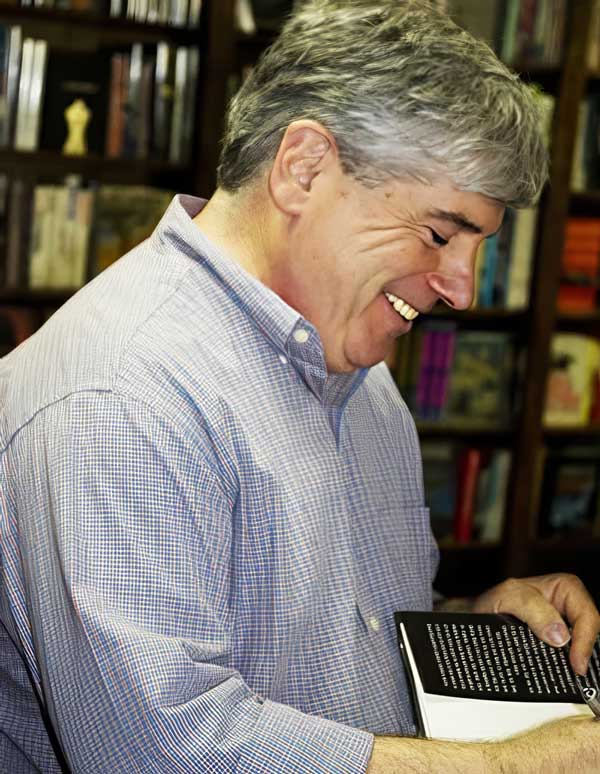 avid Rosenfelt smiling during a book signing with one of his novels in hand